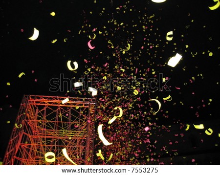 Multicolored confetti are falling down near a highlighted construction of the form of tower.