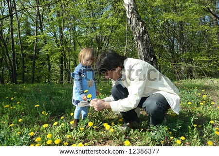 Father and daughter collecting yellow dandelions in a beautiful park