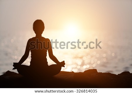 Silhouette Asia woman yoga on the beach at sunset.