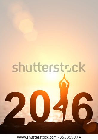 Silhouette Asia woman yoga in 2016 text on the beach at sunset. Happy new year 2016