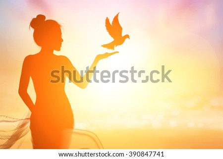 Abstract silhouette of bird flying out of lady hand on beautiful background.freedom concept