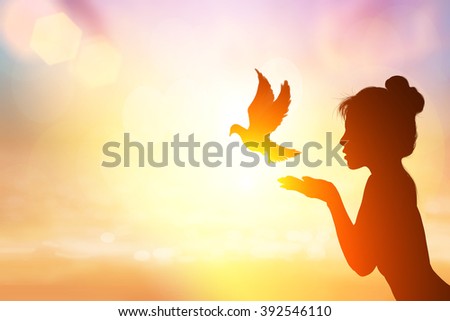 Abstract silhouette of bird flying out of lady hand on beautiful background.freedom concept
