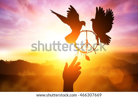 desire for peace concept with Silhouette of one hand desire to peace sign shape and dove flying on sunset sky for freedom and peace concept and  World Peace Day and hand helping