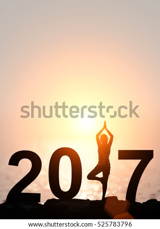 Silhouette Asia woman yoga in Happy new year 2017 text on the beach at sunset.