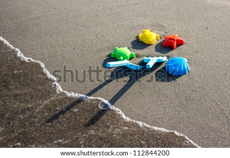 Toys on beach with wave and foam