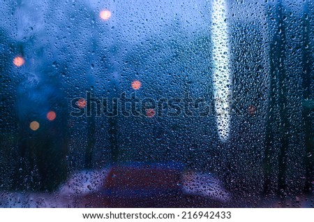 raindrops on the glass on the background of multicolored shapes windows with night light