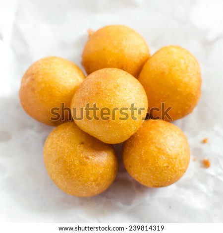 Several sugar sprinkled desserts , Yellow fried pastry balls , Thai Fried snacks
