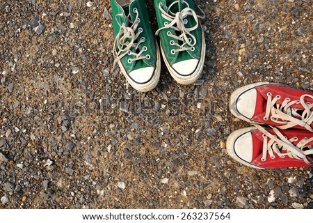 Red and green Sneakers shoes walking on gravel road , Canvas shoes walking on gravel road , two sneakers behind each others as a sign of love , Sneakers shoes Couple
