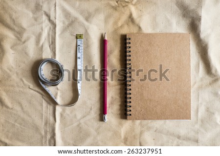 Pencil ,notebook ,tape measure on Brown canvas fabric crease, Measurement Tools on Brown canvas fabric crease