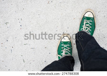 green Sneakers shoes walking on white Sand top view , Canvas shoes walking on white Sand
