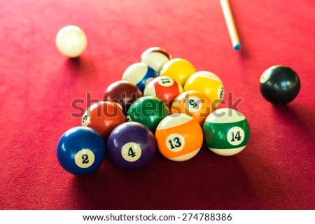 Billards pool game. Color balls in triangle, aiming at cue ball. Red cloth table , Pool balls on a red background