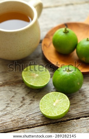 Green lemon fruit with lemon tea on wooden