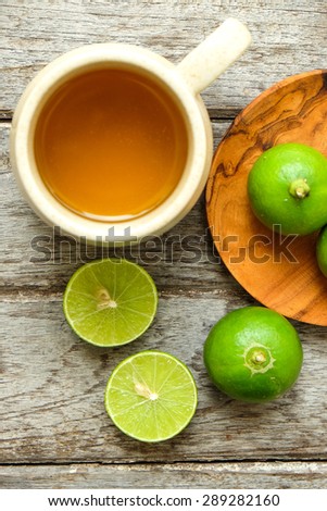 Green lemon fruit with lemon tea on wooden
