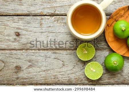 Green lemon fruit with lemon tea in cup on wooden