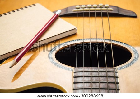 Notebook and pencil on guitar for writing music , Concept of music
