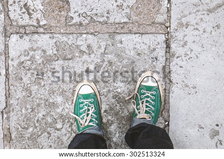 Green Sneakers shoes walking on Dirty concrete top view , Canvas shoes walking on concrete