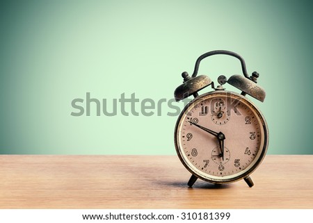 Old retro alarm clock on table with pastel background