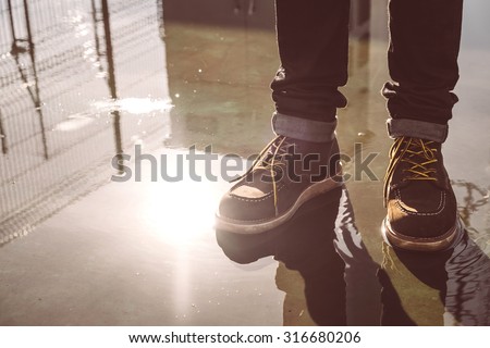 Hipster man with fashion brown leather boots on wet floor