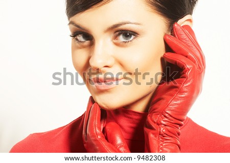 Attractive brunet in red blouse and red gloves near face
