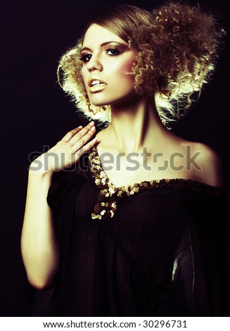 fashion model with curly hair in black tunic in black background
