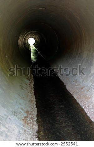 View through a long concrete pipe with a small amount of flowing water
