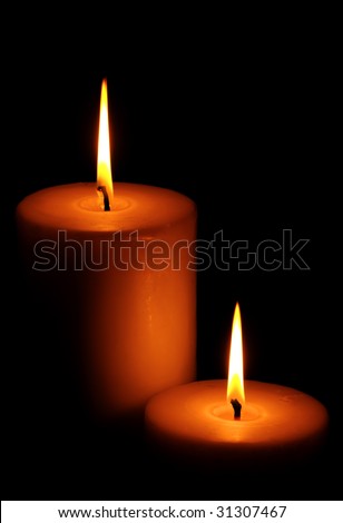Two burning candles against dark background