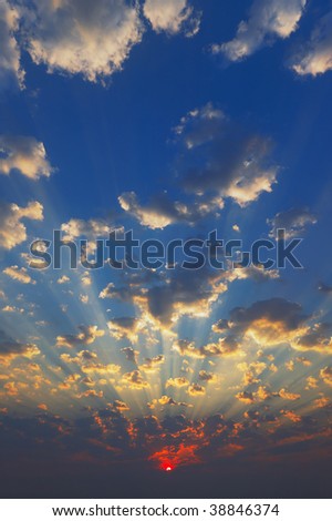 Cloudscape with sun-rays shining through clouds just as sun appears