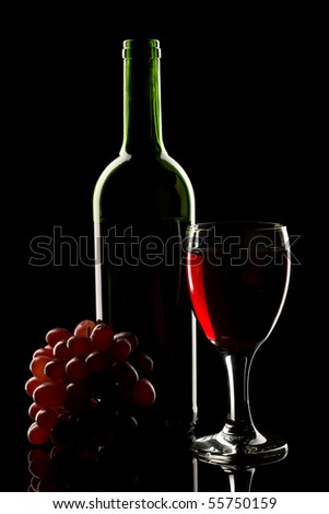 A bottle and glass of red wine with grapes