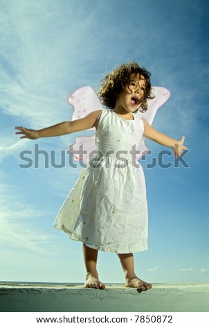 young girl with fairy wings flying against blue sky with cirrus clouds