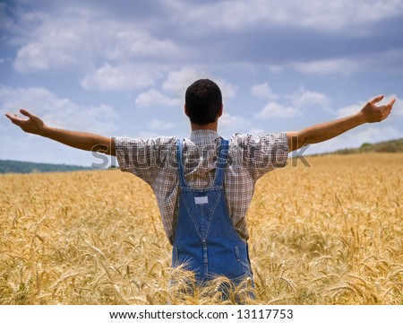 farmer standing in a wheat field with his arms spread out