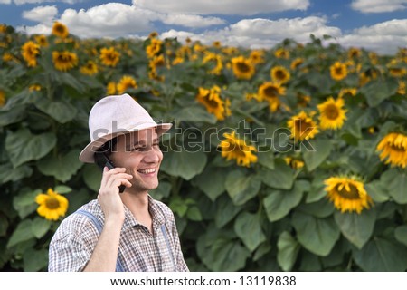 farmer standing in front of a sunflower field talking on the phone