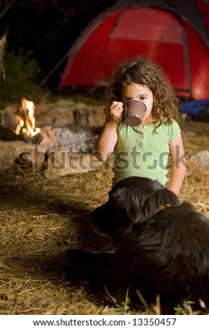 little girl drinking in a camp at night with a dog, campfire and a red tent