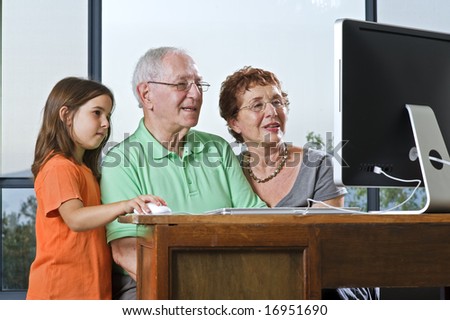 grandparents and granddaughter with computer at home
