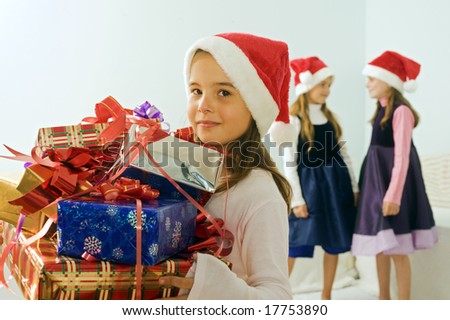 three little girls with Christmas presents and Santa hats