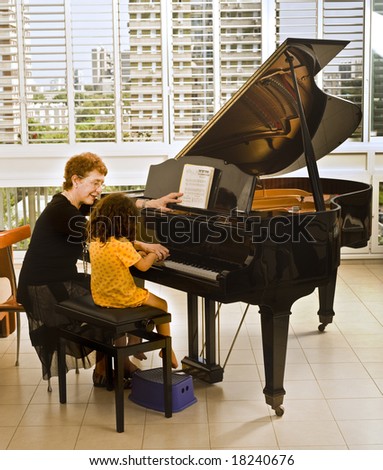 senior piano teacher with young girl student