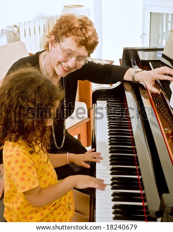 senior piano teacher with young girl student