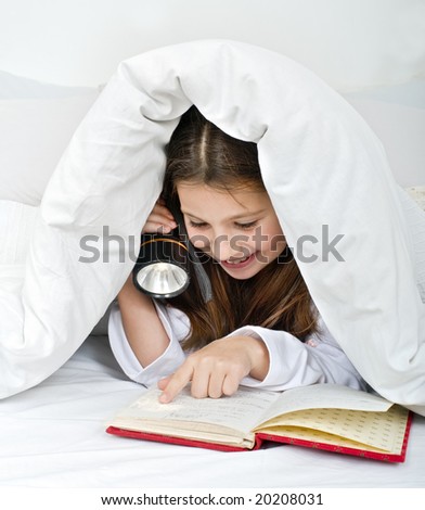 girl reading under blanket with flashlight