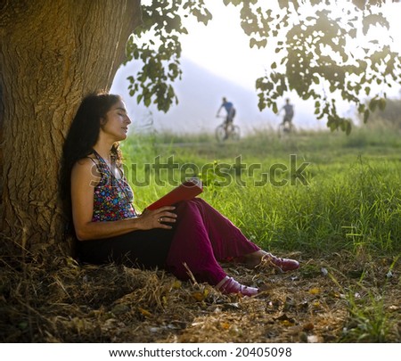 woman sitting under tree reading a book