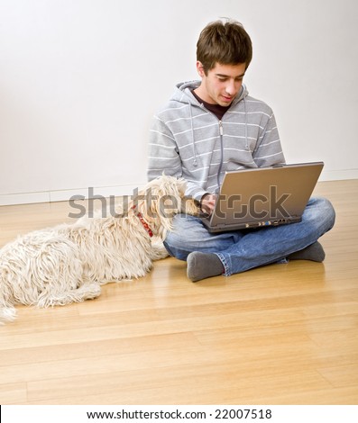 teenager with a laptop computer and his dog on a parquet floor