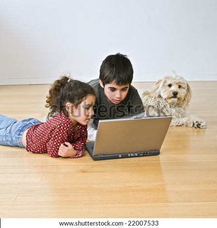 two kids and a dog with laptop computer on the floor