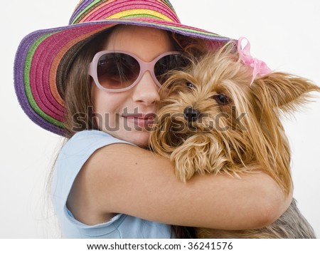 Young girl with sunglasses and hat, holding a Yorkshire terrier dog