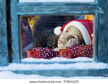 Little girl with a Santa hat  looking outside