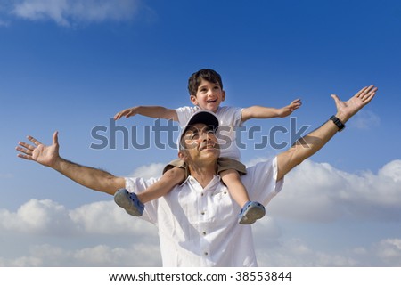 son riding on his father shoulders with spread arms