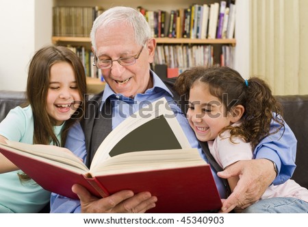 grandfather and grandchildren reading a book