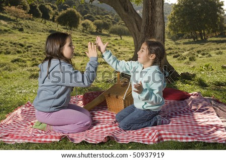 Tow girls playing a clapping game outdoor in a picnic