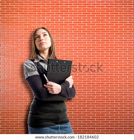 Young student thinking over brick wall background