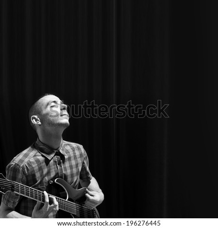 Young man playing guitar over black background