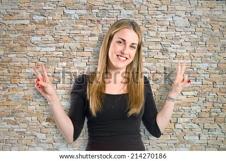 Blonde girl doing victory gesture over textured background
