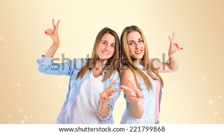 Girls doing victory gesture over gloss background