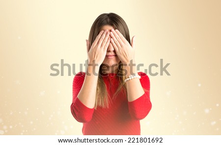 young girl covering her eyes over gloss background